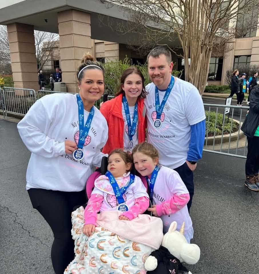 Three adults and two children wearing medals outside an event venue