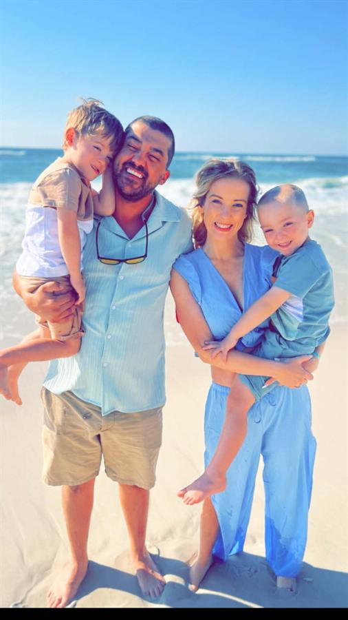 Two adults holding two children on a beach