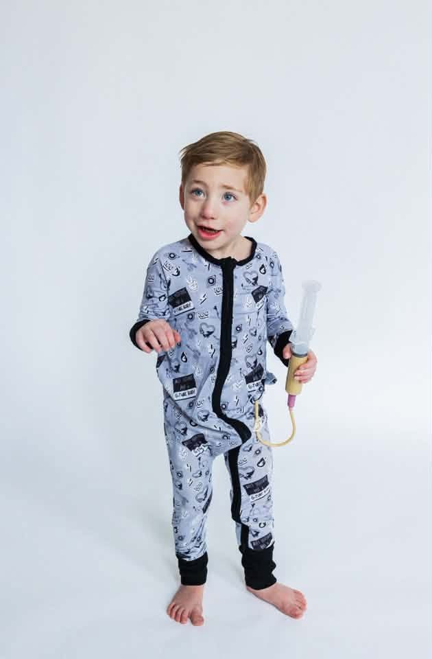 A child modeling a gray patterned one-piece outfit against a white background
