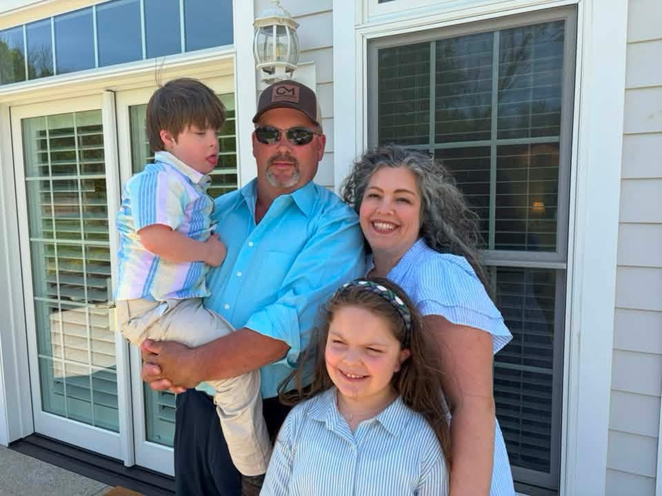 Two adults and two children standing in front of a house