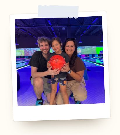 Taylor, her husband, and their daughter at a bowling alley.